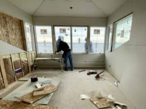 team member installing new Anderson windows from interior of home under construction