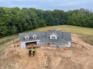 birds-eye view of new home during construction. Shingle roof, house-wrapped walls, vinyl windows