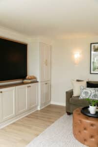 finished basement remodel corner of room with white cabinets, framed TV, and vinyl plank flooring