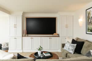 wall with white cabinets around a framed TV