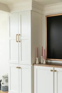 close up of candle sticks on white cabinets next to framed TV