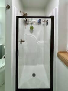 fiberglass shower that has been re-glazed and has a new black trimmed shower door and gold hardware