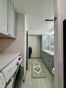 Full view of bathroom and laundry room remodel with drier, vanity cabinets, tile floor, mirror, LED lights